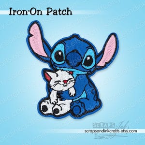 May include: Embroidered iron-on patch depicting a blue cartoon character embracing a white cat. The character has large ears with pink inner ears and large blue eyes. The patch has the words "Iron-On Patch" at the top.