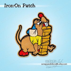May include: Embroidered iron-on patch featuring a cartoon character in a yellow shirt and blue hat, hugging a stack of pancakes. The patch has a brown border and the text "Iron-On Patch".