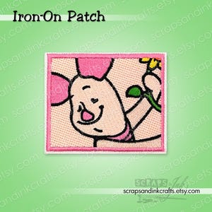 May include: An embroidered iron-on patch featuring a cartoon pig holding a flower. The pig is pink and white with a pink bow and a smiling face. The patch has a pink border and the text "Iron-On Patch" at the top.
