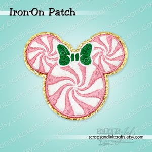 May include: An iron-on patch shaped like a mouse head made of three pink and white peppermint swirl candies. The patch features a green bow between the ears and is outlined with a gold glitter border. The text Iron-On Patch is at the top.