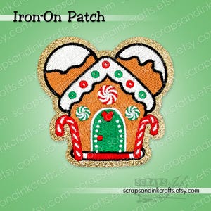 Op de afbeelding: Geborduurde opstrijkbare patch in de vorm van een peperkoekhuisje met Mickey Mouse oren. De patch heeft bruine, witte, rode, groene en gouden kleuren. De tekst "Iron-On Patch" staat bovenaan. Een feestelijke vakantieversiering.