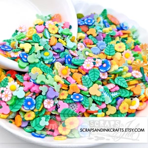 May include: A bowl filled with colorful polymer clay sprinkles. The sprinkles are shaped like flowers, leaves, Mickey Mouse heads, and other small shapes. The sprinkles are perfect for adding a touch of whimsy to crafts and projects.