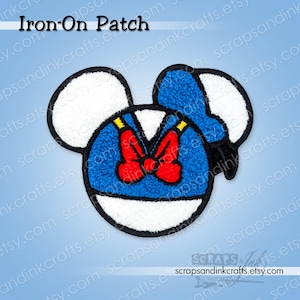 May include: An iron-on patch featuring a cartoon character's face. The patch has a blue, white, red, and yellow color scheme. The character's face is outlined in black, with white ears and a blue hat. A red bow tie is centered on the chest.