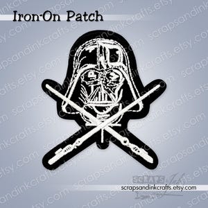 May include: Black and white iron-on patch featuring Darth Vader's helmet and crossed lightsabers. The patch has a black border and the text "Iron-On Patch" at the top. A Star Wars themed item.