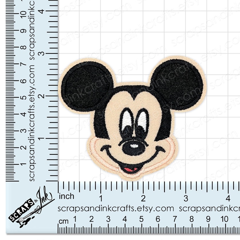 Pode incluir: Patch bordado com o rosto do Mickey Mouse. O patch tem um fundo bege com orelhas e contornos pretos. O rosto inclui olhos brancos, um nariz preto e uma boca vermelha. O patch mede aproximadamente 7.6 cm de altura.