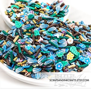 May include: A bowl filled with colorful sprinkles in various shapes, including leaves, stars, flowers, and sticks. The sprinkles are a mix of blue, green, brown, and white.