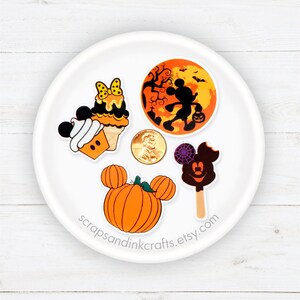 Pu&ograve; includere: Cinque adesivi di personaggi Disney a tema Halloween su un piatto bianco. Gli adesivi raffigurano Topolino, Minnie Mouse, una zucca, un gelato al cioccolato Mickey Mouse e un cono gelato Mickey Mouse.