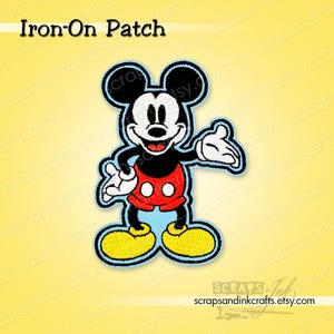 May include: An iron-on patch featuring Mickey Mouse. The patch shows Mickey in his classic outfit: red shorts, yellow shoes, and white gloves. The patch has a light blue border and the text "Iron-On Patch" at the top.