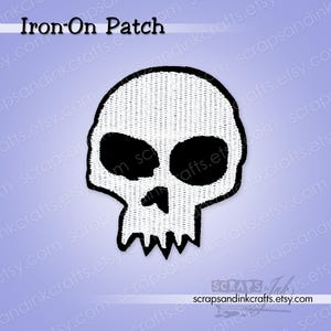 Op de afbeelding: Een zwart-wit strijkapplicatie met een schedel. De schedel heeft grote, zwarte oogkassen en een grillige kaaklijn. De patch is zwart omlijnd en heeft bovenaan de tekst "Iron-On Patch".