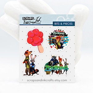 May include: Four stickers featuring characters from the animated movie Zootopia. The stickers include a paw print popsicle, a scene with Nick Wilde and Judy Hopps, a scene with Nick Wilde, Judy Hopps, and Chief Bogo, and a scene with Nick Wilde, Judy Hopps, and Flash. The stickers are on a white background with the text "Scraps & Ink" and "Bits & Pieces" at the top.