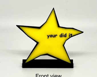 May include: A yellow star-shaped trophy with black trim and a black base. The text "your did it" is printed on the star. The words "Front view" are printed below the trophy.
