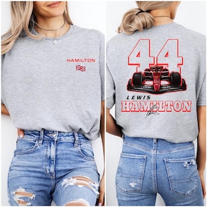May include: Gray t-shirt with "HAMILTON" and a British flag printed on the left side. The back of the shirt has a red race car with the number "44" and "LEWIS HAMILTON" printed in red.