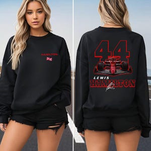 Peut inclure: Sweat-shirt noir avec un graphique de voiture de course de Formule 1 rouge et blanc au dos. La voiture porte le numéro 44 et le texte "Lewis Hamilton". Le devant du sweat-shirt porte le texte "Hamilton" et un petit drapeau britannique.