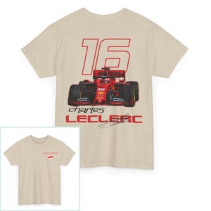 May include: A beige t-shirt with a red and white image of a race car with the number 16 on it. The text "charles LECLEC" is printed below the car. The t-shirt has short sleeves and a crew neck.