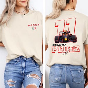 May include: A beige t-shirt with the number "11" and the name "Sergio Perez" printed on the back. The number is in red and the name is in red and black. A Formula 1 race car is printed in the center of the number. The shirt also has a small Mexican flag printed on the front.