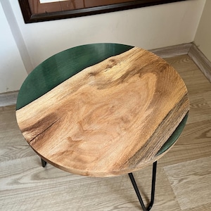 May include: A round wooden side table with a green epoxy resin inlay. The table has a black metal frame with hairpin legs.