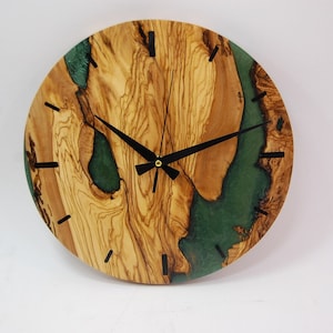 May include: A round wooden clock with a green epoxy resin inlay. The clock face has black hands and black Roman numeral markings.