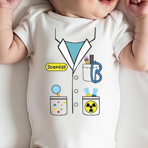 May include: White baby bodysuit featuring a printed lab coat design. The design includes a blue collar, pockets with science-themed illustrations, and the word "Scientist" in a yellow oval.