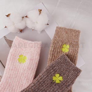 May include: Three pairs of socks with a four-leaf clover design. One pair is pink, one is brown, and one is a darker brown.