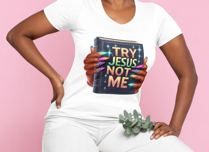 May include: White t-shirt with a graphic of a book with the text "TRY JESUS NOT ME" in colorful rhinestones.