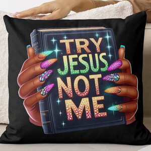 May include: Black throw pillow with a colorful graphic of a hand holding a book with the text "TRY JESUS NOT ME" in sparkly letters.