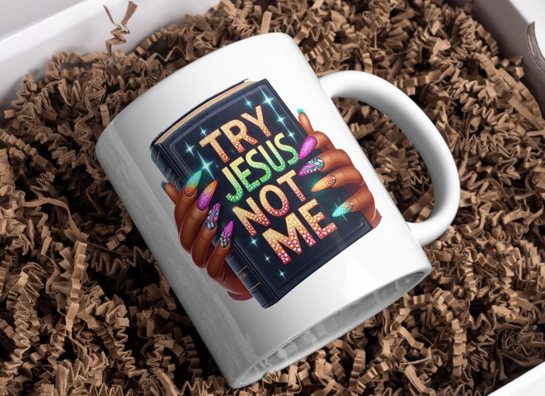 May include: White ceramic mug with a black book design featuring the text "Try Jesus Not Me" with colorful glitter accents and a hand with colorful nail polish holding the book.