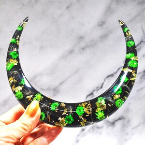 May include: A black crescent moon-shaped resin tray with green and gold accents. The tray is filled with green flowers and gold flakes.