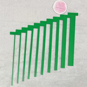 May include: A set of ten green plastic rulers with measurements in millimetres, ranging from 4 mm to 20 mm.