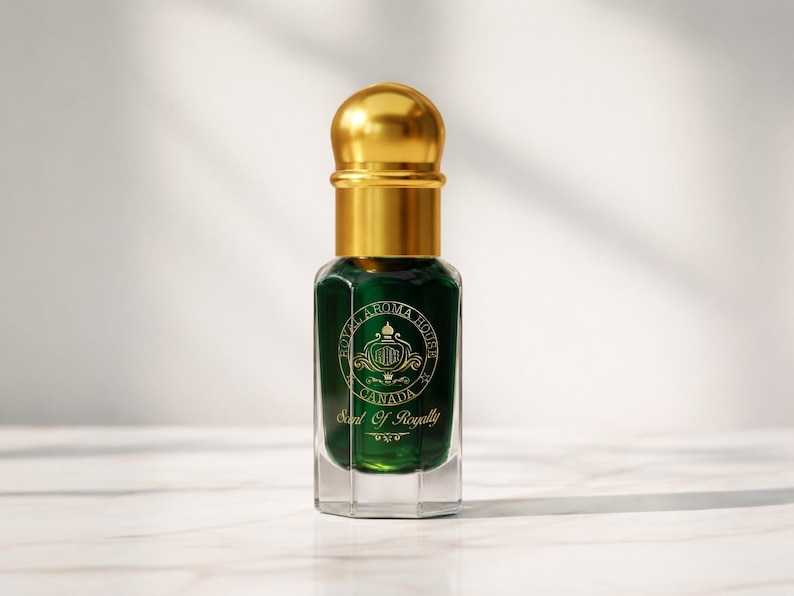 May include: A small, emerald green perfume bottle with a gold cap. The bottle has a clear, octagonal base and a gold label with the text "Royal Aroma House Canada" and "Scent Of Royalty". The background is a soft white.