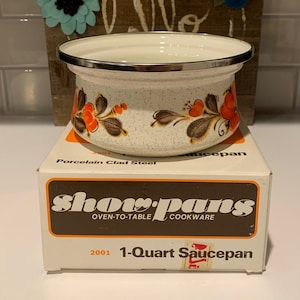 Puede incluir: Una cacerola blanca de 1 litro con un diseño floral en naranja, marrón y blanco. La cacerola está hecha de acero revestido de porcelana y es parte de un juego de utensilios de cocina para horno y mesa.