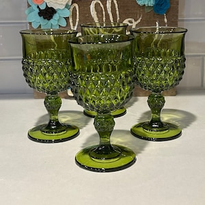 May include: Set of four green glass goblets with a diamond pattern. The goblets have a tall stem and a wide bowl.
