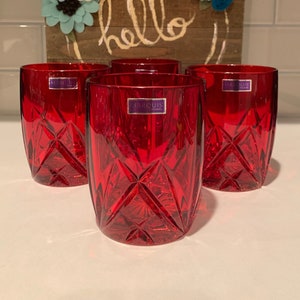 May include: Set of four red glass tumblers with a diamond pattern. The tumblers have a Marquis label on the bottom.