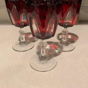 Peut inclure: Ensemble de trois verres à vin rouge rubis avec des tiges et des bases claires. Les verres ont un design facetté.