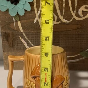 May include: A brown ceramic mug with a mushroom design. The mug is 4 inches tall and has a handle.