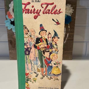 May include: Vintage "The Tall Book of Fairy Tales" with a green spine. The cover features colorful illustrations of fairy tale characters. The book's title is in red script. Published by Harper & Brothers, established in 1817.
