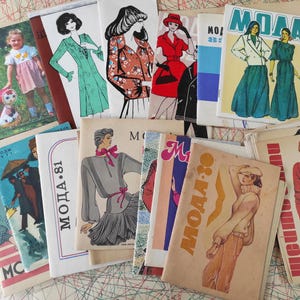 Könnte beinhalten: Eine Sammlung von Vintage-Schnittmusterbüchern mit dem Wort "Moda" auf den Umschlägen. Die Bücher sind in verschiedenen Farben, darunter Rot, Blau, Grün und Braun. Die Umschläge zeigen Illustrationen von Kleidungsdesigns.