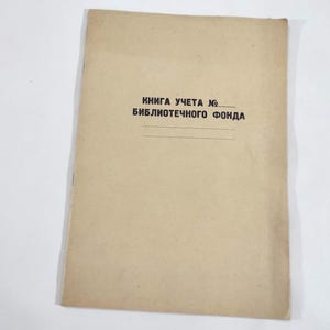 May include: A vintage book cover in a tan color, with text in black. The text reads "Kнига учета №. Библиотечного фонда" with two horizontal lines below. The book appears to be old and worn.
