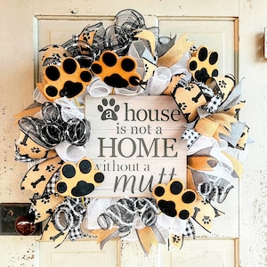 May include: A white wooden sign with the text "a house is not a HOME without a mutt" surrounded by a wreath with black, white, and gold ribbon, paw prints, and dog bone designs.