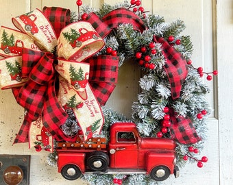 May include: A red and black buffalo plaid ribbon bow with the text "Special Delivery" is tied around a green Christmas wreath with red berries. A red toy truck with a white bed is attached to the wreath.