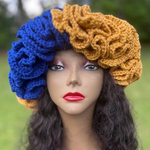 May include: A crocheted hat with a blue and gold design. The hat is made of soft yarn and has a unique, ruffled texture.