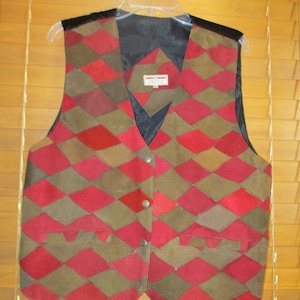 May include: A red and brown suede vest with a diamond pattern. The vest has a black lining and a label that reads "Gucci" on the front.