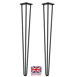 May include: Two black metal hairpin legs for furniture. Each leg has a square top plate and three prongs. The legs are approximately 70 cm tall.
