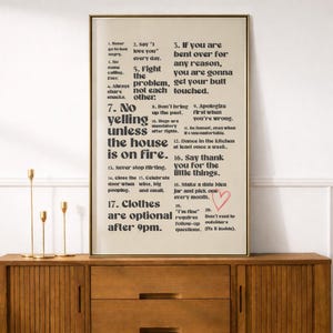 Puede incluir: Una impresi&oacute;n enmarcada con un fondo beige y texto negro. El texto enumera reglas para una relaci&oacute;n, incluyendo "Di 'Te amo' todos los d&iacute;as" y "No grites a menos que la casa est&eacute; en llamas". Un coraz&oacute;n rojo est&aacute; dibujado en la impresi&oacute;n.