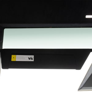 Puede incluir: Una visera parasol negra con una etiqueta de advertencia amarilla que dice "Airbag - No obstruir". La visera está extendida y está unida a un interior de coche negro.