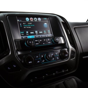 May include: A black car dashboard with a touchscreen display showing a radio station playing music. The display also shows the time, temperature, and other information. The dashboard has several buttons and knobs for controlling the radio, climate control, and other vehicle functions.
