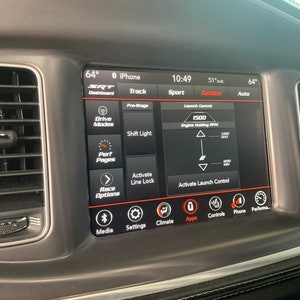 May include: A car dashboard with a touchscreen display showing the SRT Dashboard, Track, Sport, Custom, and Auto modes. The display also shows the temperature, time, and engine RPM. The screen has icons for media, settings, climate, apps, controls, phone, and performance.