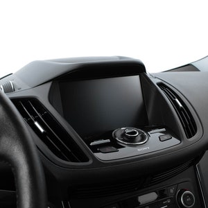 May include: A black car dashboard with a touchscreen display that says "SONY" and has a knob and buttons. The dashboard also has air vents and a steering wheel.