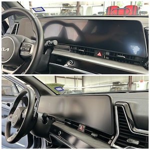May include: A close-up of the interior of a car with a large, black, digital dashboard display. The dashboard is made up of two screens, one for the instrument cluster and one for the infotainment system. The car has a black steering wheel and a black leather interior.