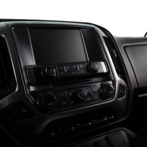 May include: A black dashboard with a large touchscreen display and a row of buttons below. The buttons are labeled "AUTO", "AC", and "RECIRC".