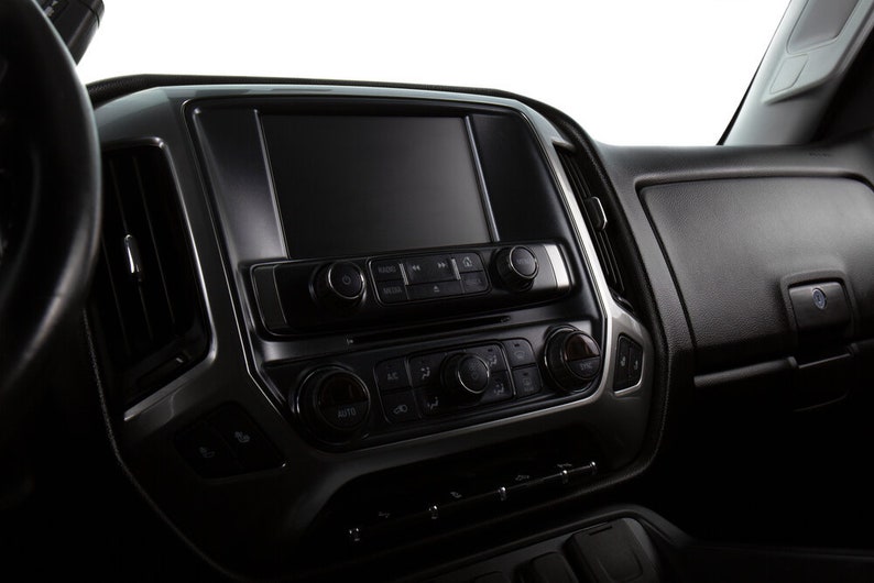 May include: A black dashboard with a large touchscreen display and a row of buttons below. The buttons are labeled "AUTO", "AC", and "RECIRC".